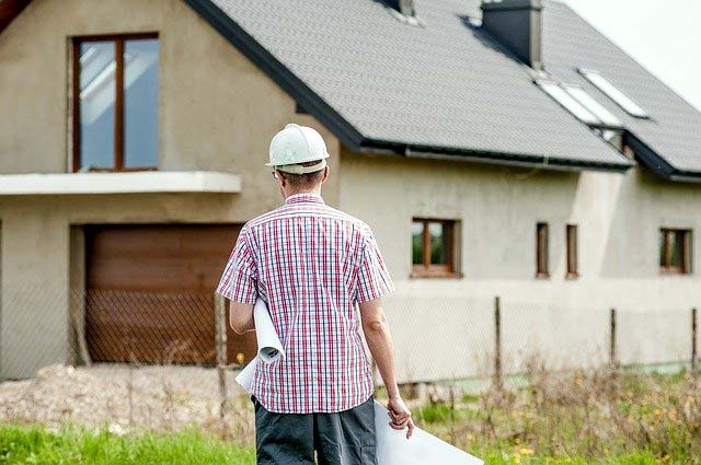 Photo of an architect with house plans looking at home