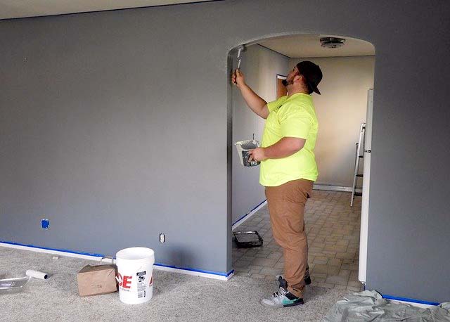 Photo of a man painting a living room